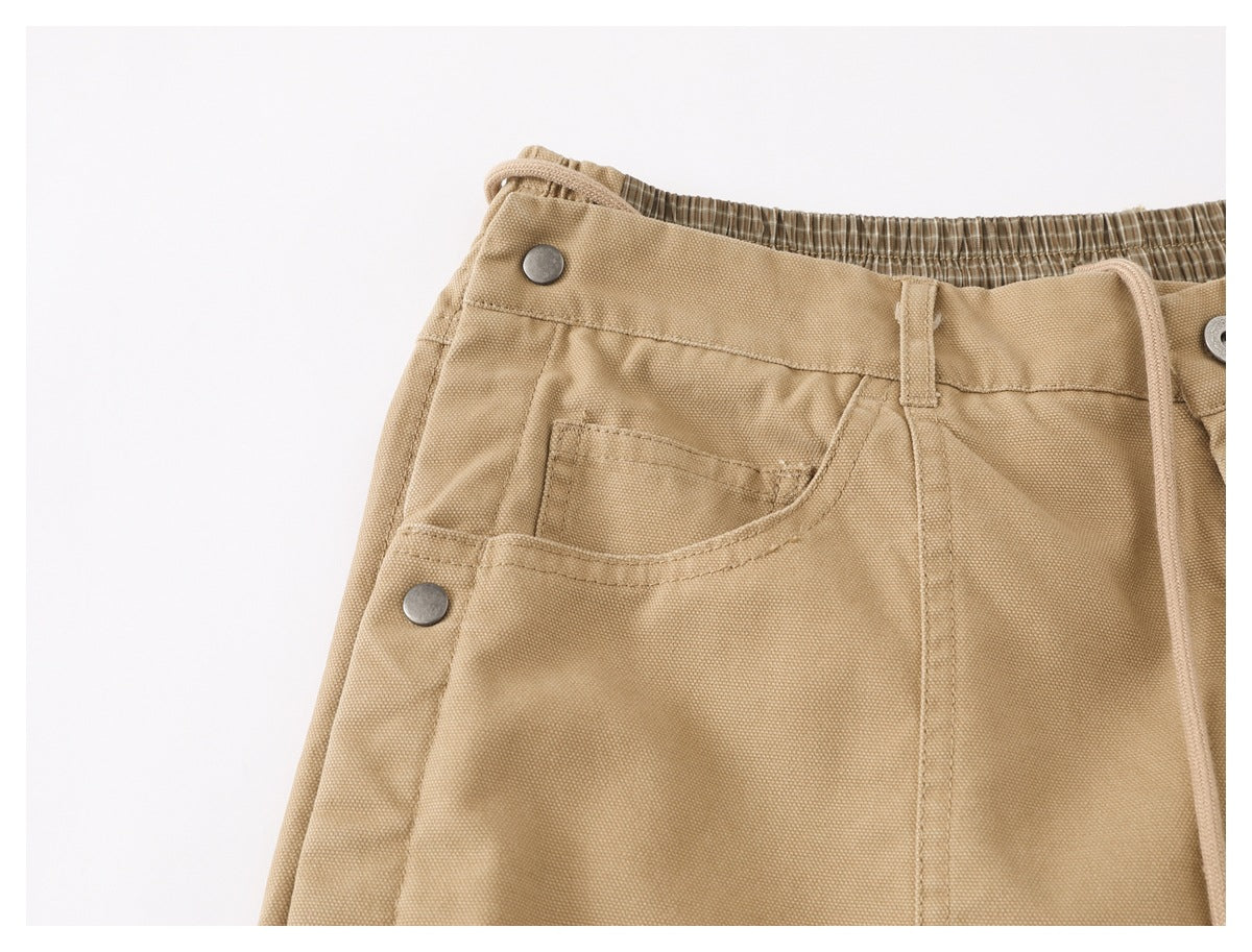 Close-up of the tan pants' front pocket, waistband, and metal snap detail.