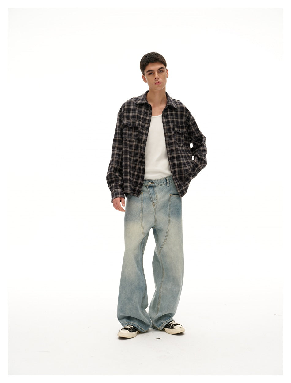 Model wearing an open black plaid shirt over a white tank top with light-wash wide-leg jeans and sneakers
