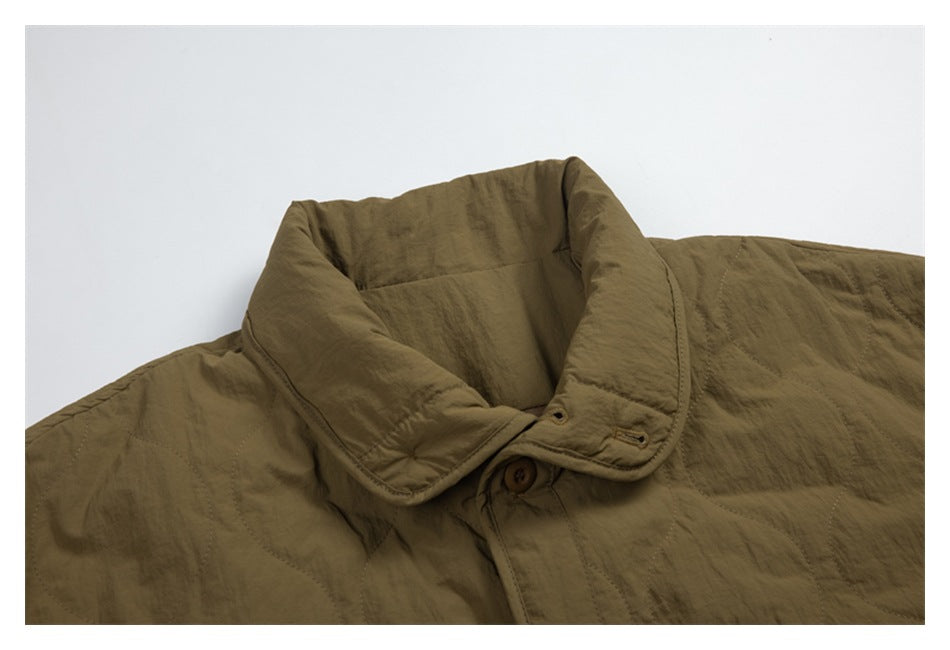 Close-up of the olive quilted jacket's wide collar, button fastening, and stitched fabric.