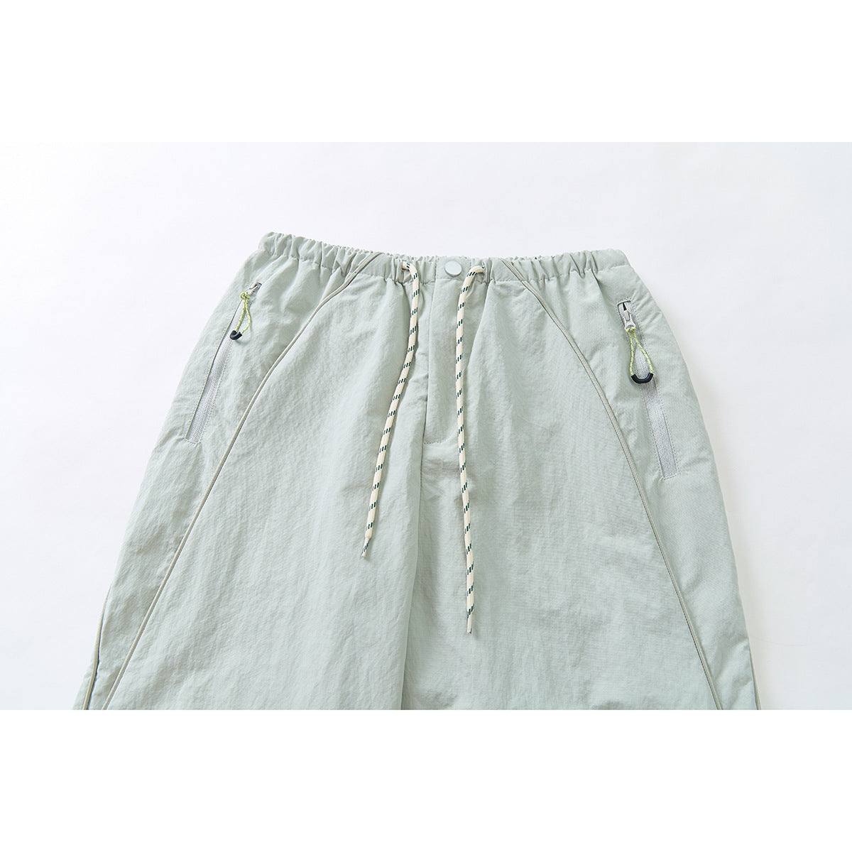 Cropped front view of pale sage wide-leg pants with an elastic drawstring waist and zippered pockets.