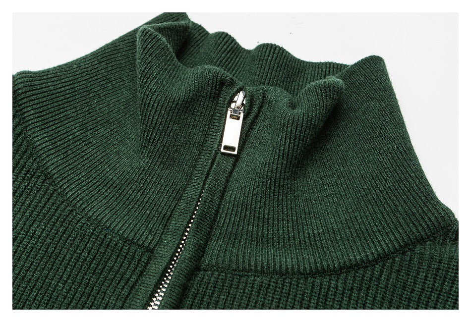 Close-up of a dark green rib-knit garment's stand collar and silver front zipper.