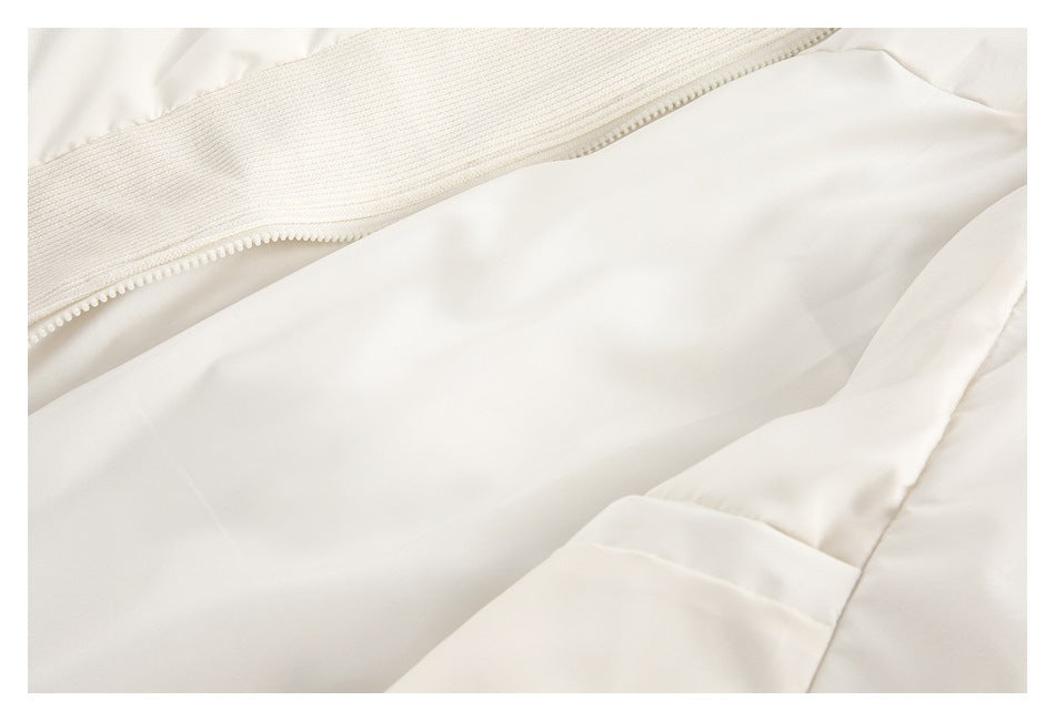 Close-up of an off-white garment with a zipper and stitched fabric panels.