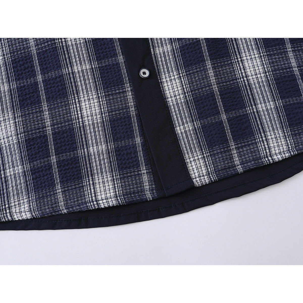 Close-up of the blue-and-white plaid shirt’s lower front, button placket, and solid navy hem.