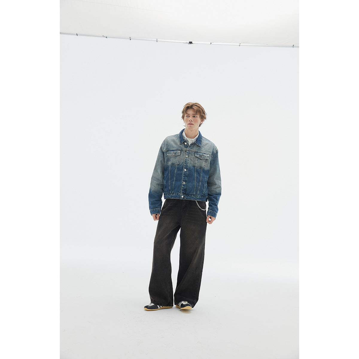 Full-length front view of a model wearing a faded blue denim jacket with chest pockets and black wide-leg pants.