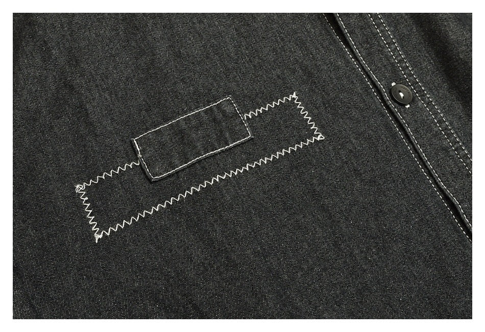 Charcoal shirt detail showing a rectangular patch, angular white zigzag stitching, and part of the button placket.
