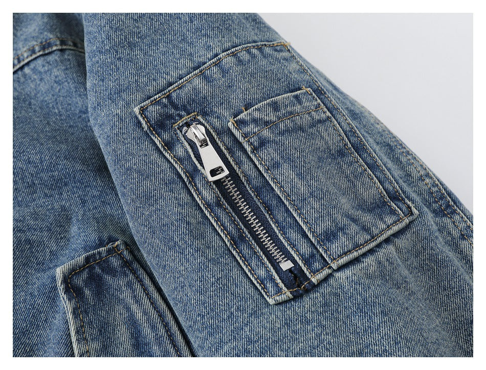 Close-up of a blue denim sleeve with a vertical zip pocket and a separate flap pocket.