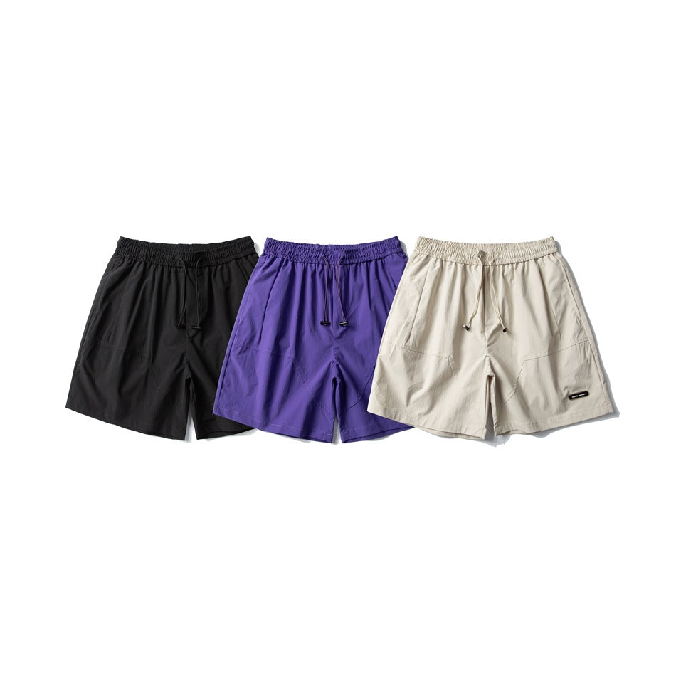 Three pairs of drawstring shorts shown from the front in black, purple, and cream.