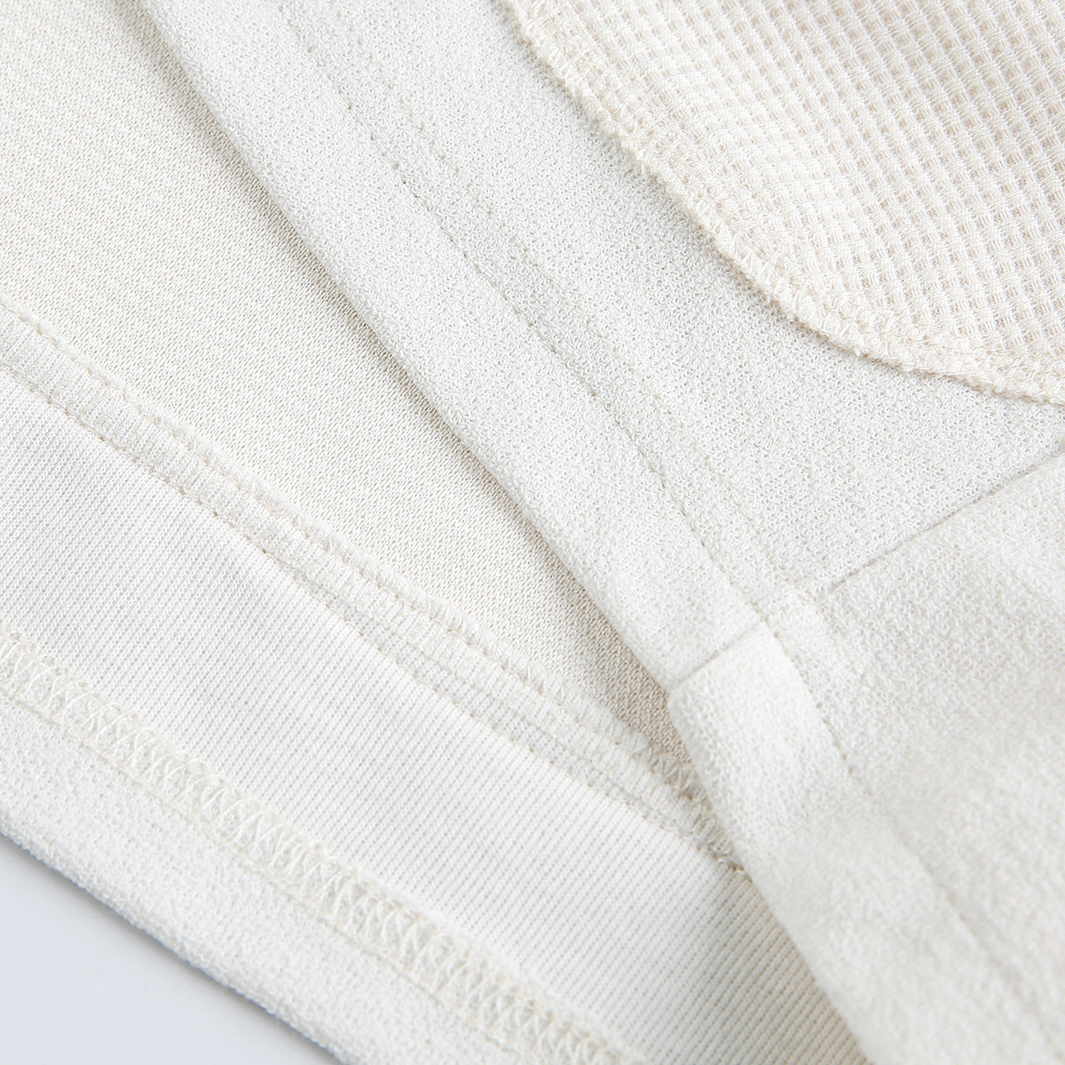 Close-up of white shirt fabric and stitched seams.