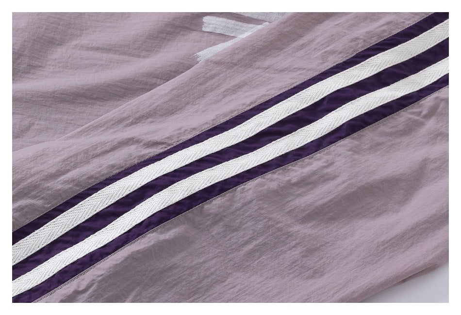 Close-up of parallel purple and white stripes on mauve fabric.