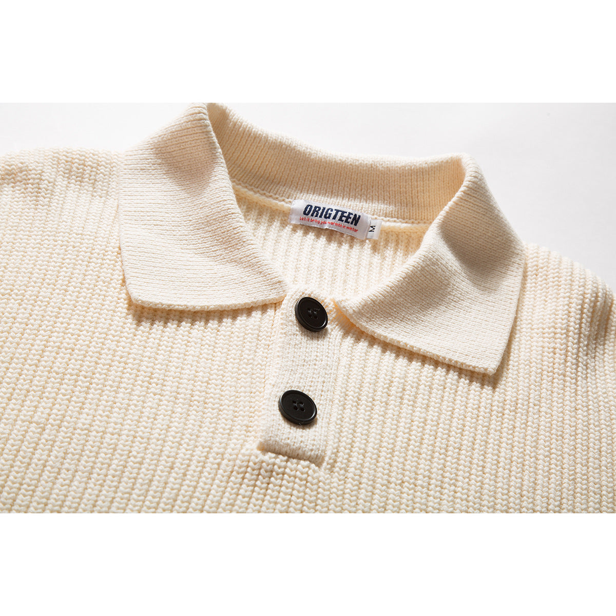 Close-up of an ivory knitted polo sweater showing its wide collar, two dark buttons and neck label.