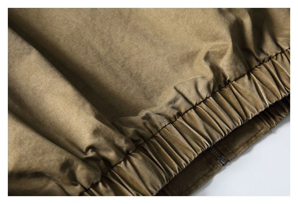 Close-up of a gathered elastic waistband and zipper on a khaki-brown garment.