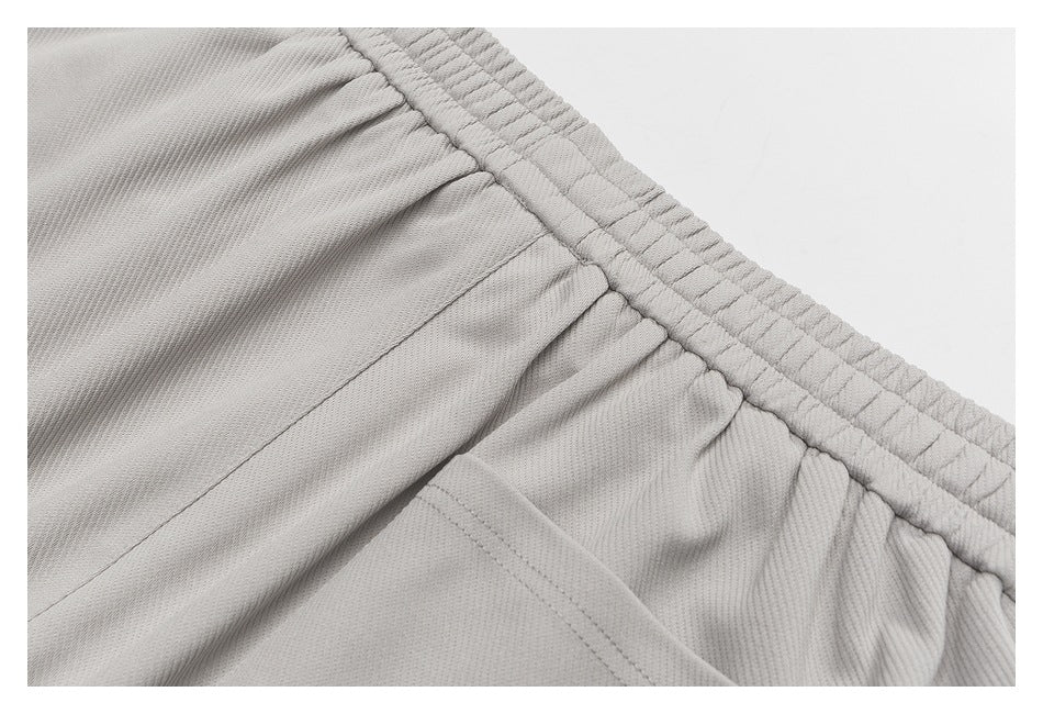 Close-up of a light gray garment's gathered elastic waistband and pocket stitching.