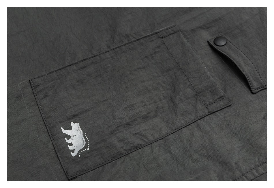 Close-up of a charcoal-gray pocket with a small white animal-like graphic and a snap-tab detail.