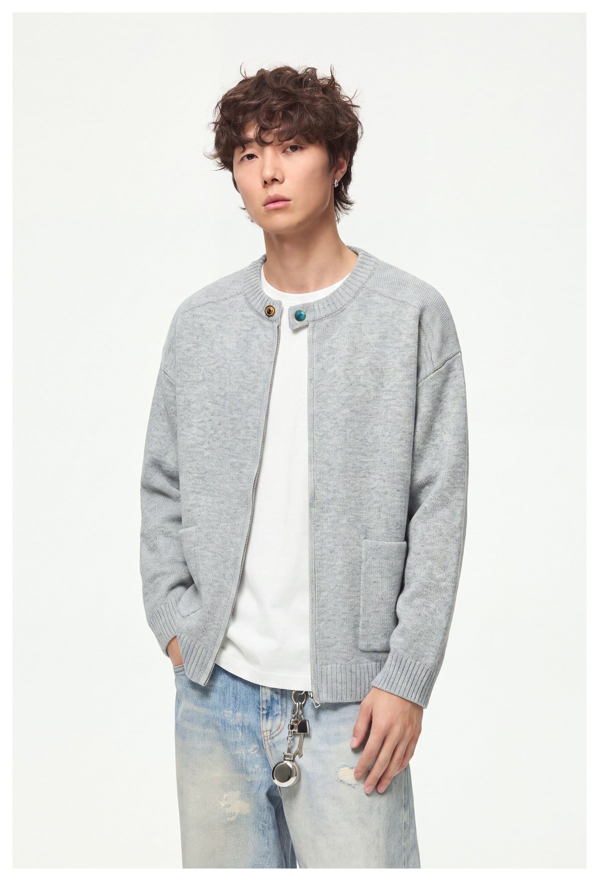 Close view of a model wearing a light gray cardigan with a front zipper, ribbed trim, and patch pockets.