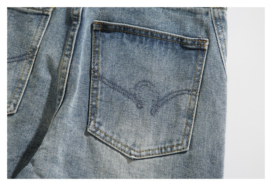Close-up of a light-wash jeans back pocket with contrasting stitching and curved tonal embroidery.