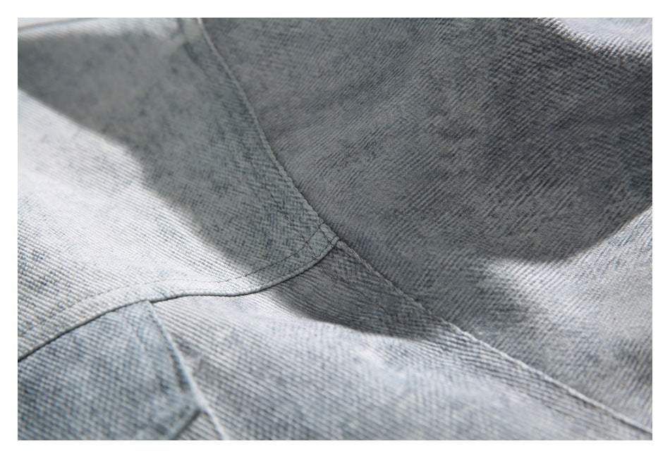 Close-up of intersecting seams and panel stitching on light gray denim fabric.
