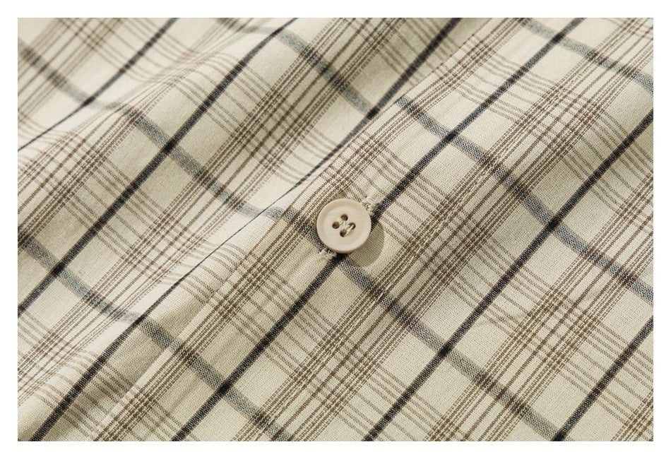 Macro view of beige plaid shirt fabric with a cream-colored button.