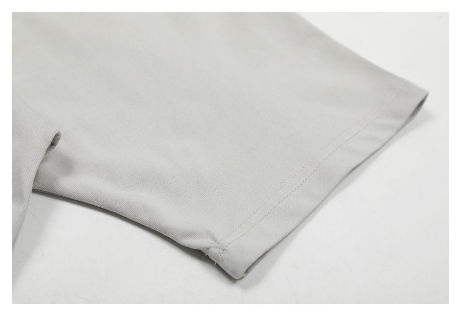 Close-up of a light gray garment sleeve edge with a stitched hem.