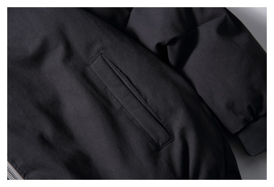 Close-up of a black jacket's angled welt hand pocket and ribbed sleeve cuff.