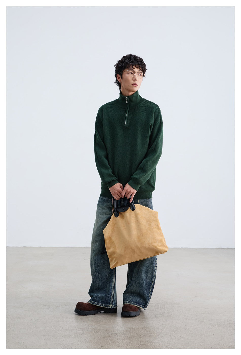 Full-length model wearing a dark green quarter-zip pullover with jeans and holding a tan tote bag.