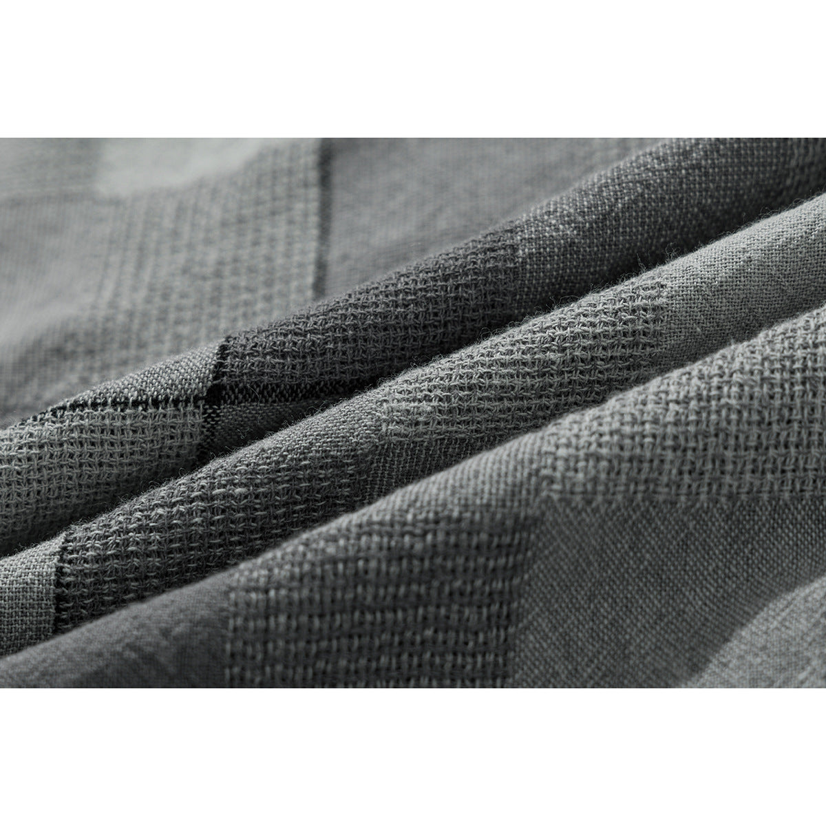 Extreme close-up of the gray checked shirt fabric, showing its woven texture and folds.