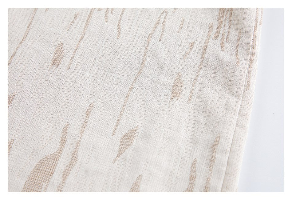 Close-up of pale cream woven fabric with subtle tan abstract streaks.