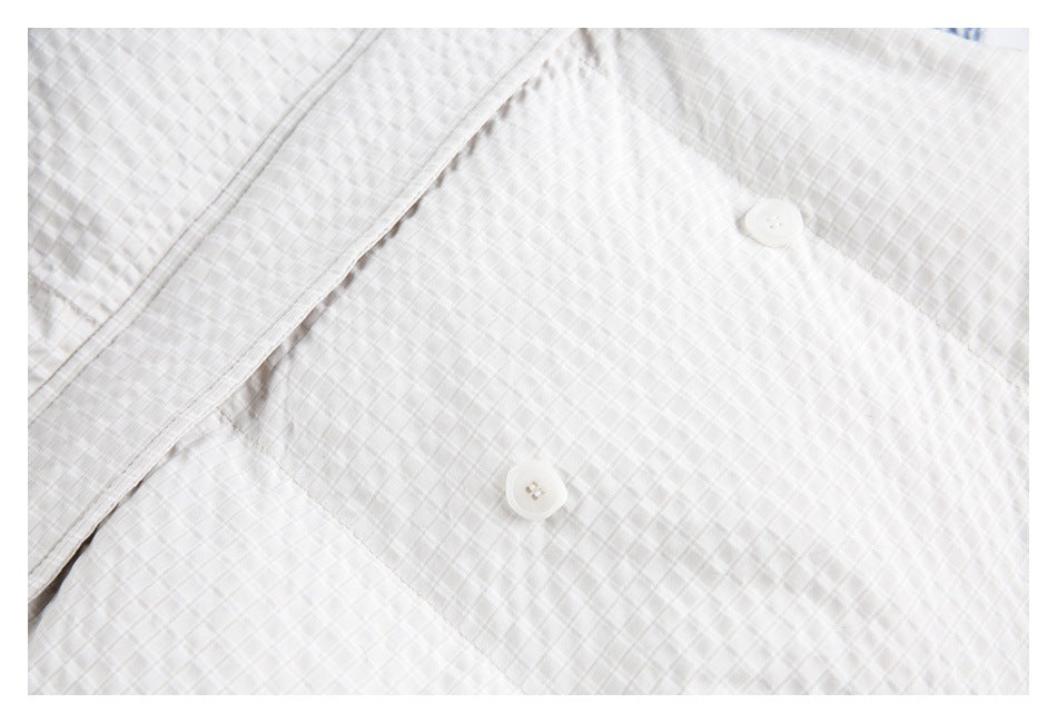 Close-up of two white buttons on the front of a white quilted jacket.