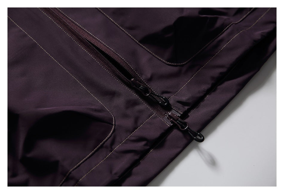 Close-up of two dark zippers with pull tabs on a dark plum garment.