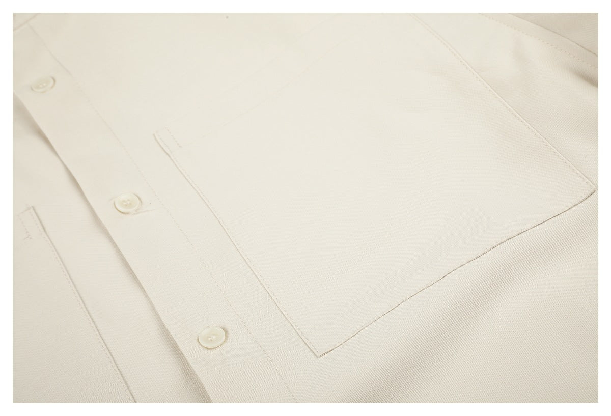 Close-up of an off-white patch pocket and button placket on the shirt front.