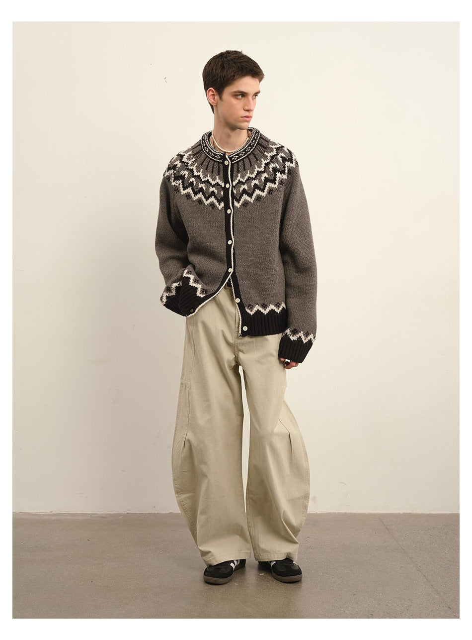 Model wearing a charcoal button-front cardigan with cream Nordic-style patterning and wide beige trousers.
