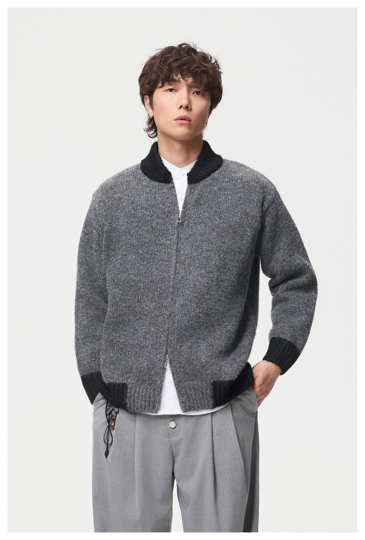 Close front view of a model wearing a dark gray zip-front knit jacket with a black ribbed collar and cuffs.