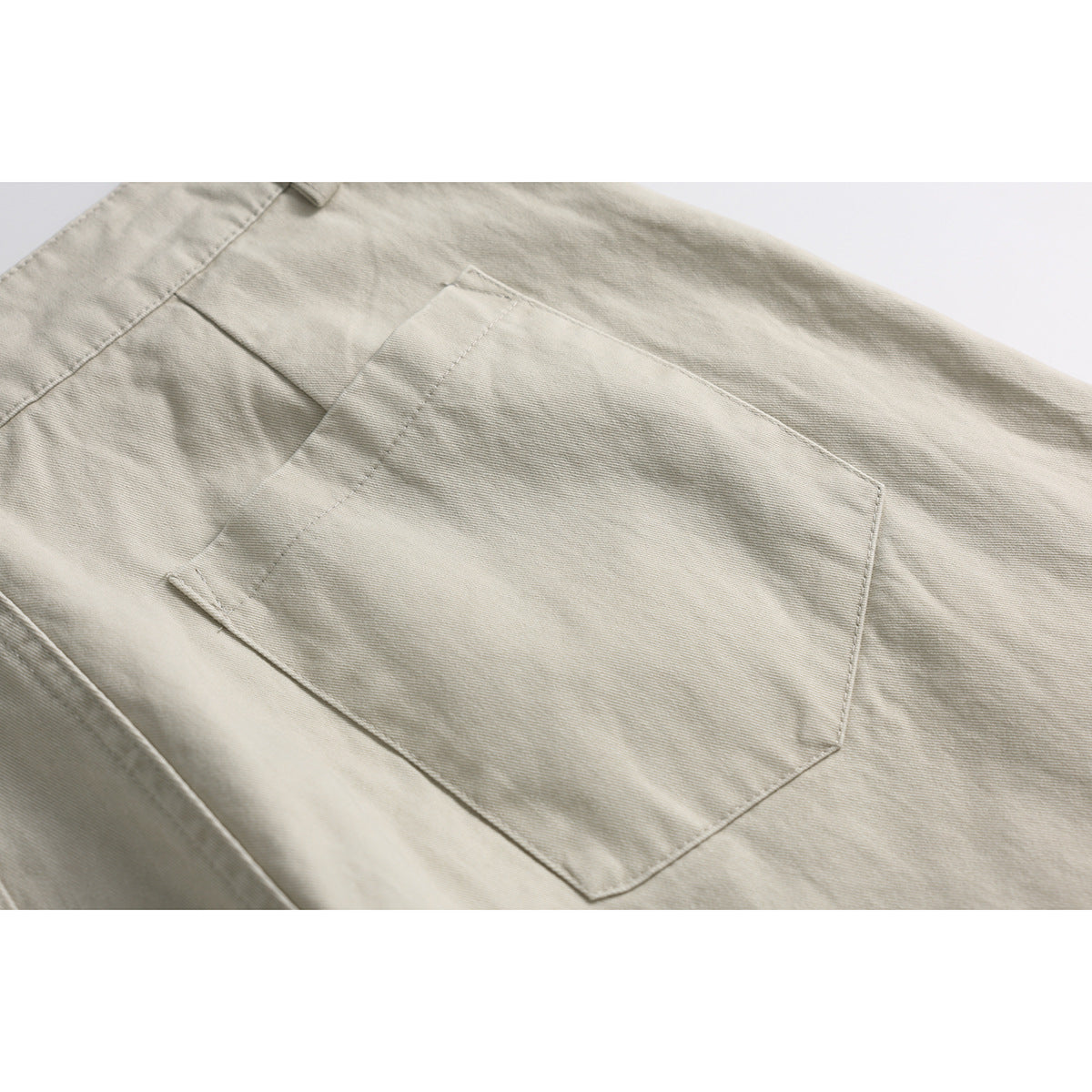 Close-up of light beige shorts showing a large rectangular back pocket and stitching.
