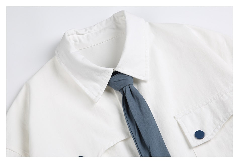 Close-up of the white shirt collar, blue necktie, and flap chest pocket with a blue button.