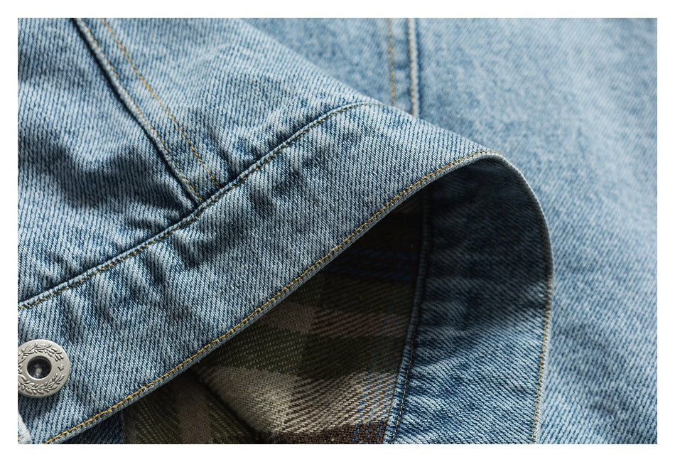 Close-up of an opened denim jacket cuff showing its plaid lining and contrast stitching.