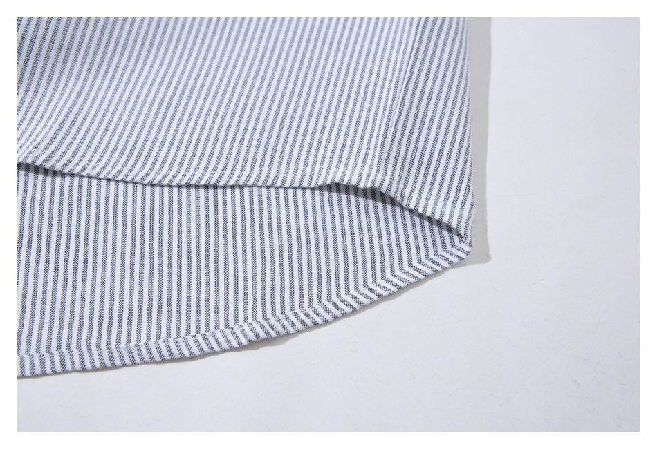 Close-up of the curved hem of a white shirt with fine gray stripes.