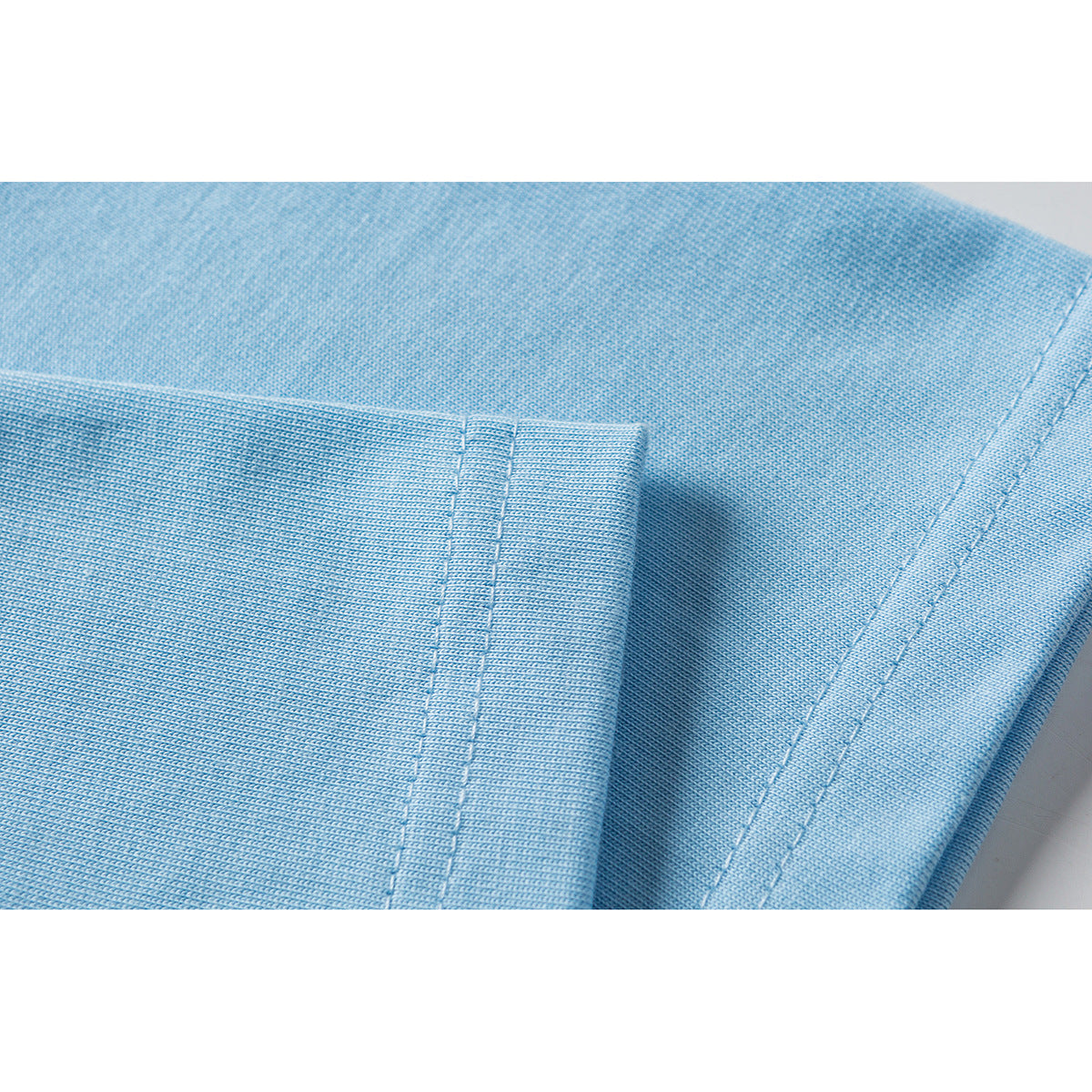Close-up of light blue T-shirt fabric showing the sleeve and hem stitching.