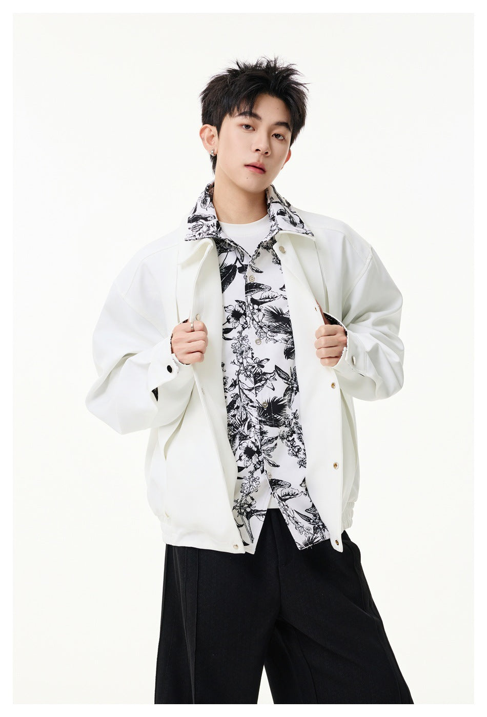 Model wearing a white snap-front jacket with black floral-print collar and trim, open over a matching printed shirt.