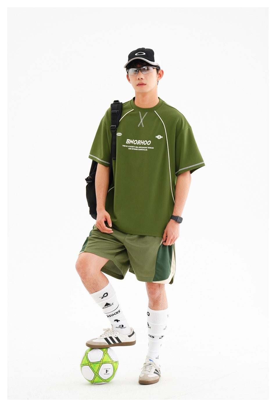 Front view of a man wearing an olive-green graphic sports T-shirt and matching color-block shorts.
