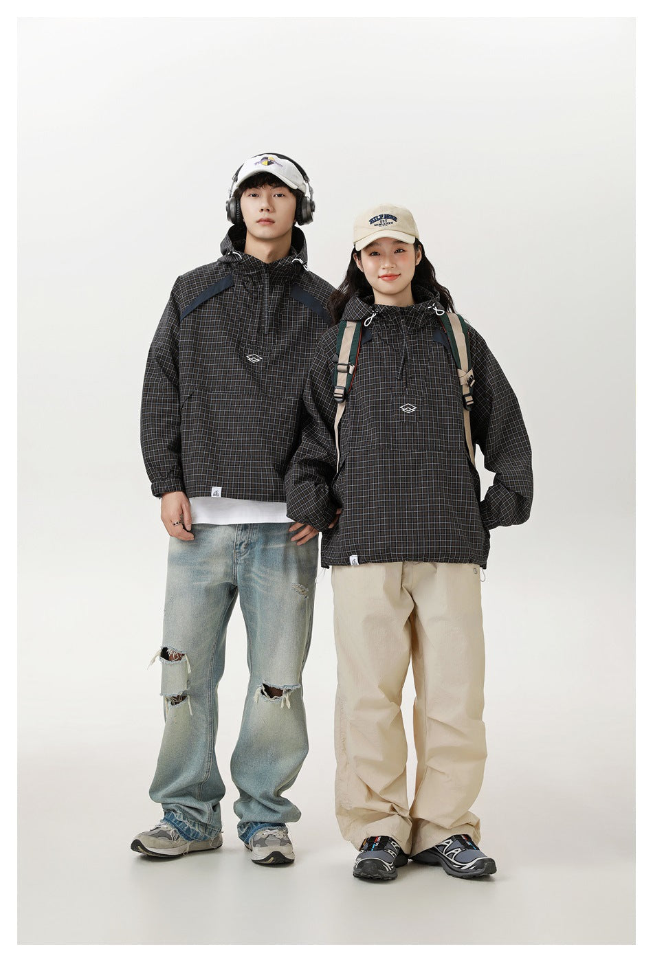 Man and woman model matching black checked hooded pullover jackets with front pockets and drawstrings.