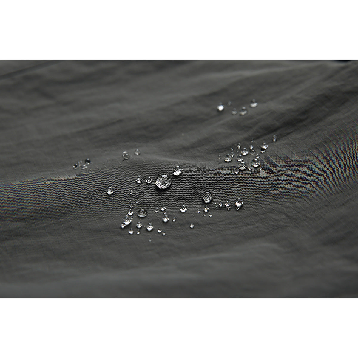 Water droplets bead on the dark, finely gridded surface of the pants fabric.