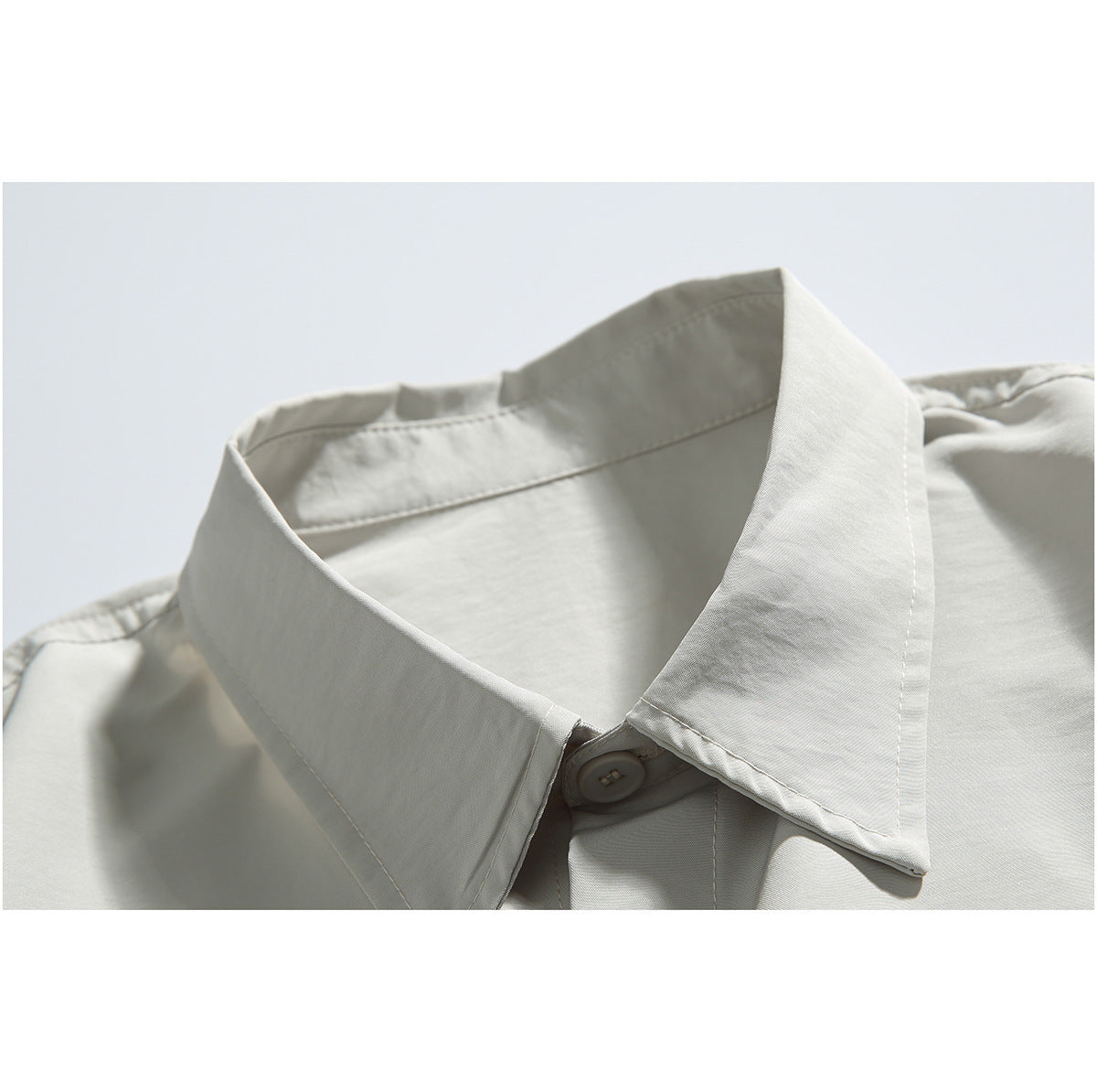 Close-up of a light gray collared shirt showing the pointed collar and top button.