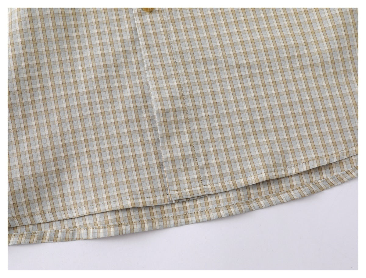 Close-up of the stitched hem on a beige, white, and muted brown plaid shirt.