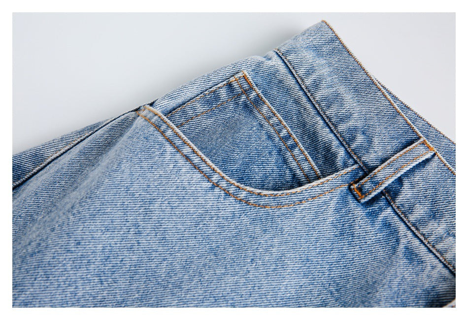 Close-up of a front pocket opening and belt loop on light-wash jeans with contrast stitching.
