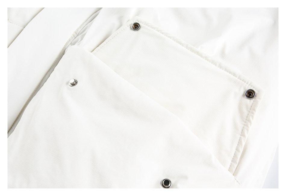 Close-up of a white garment panel with several round metal snap fasteners.