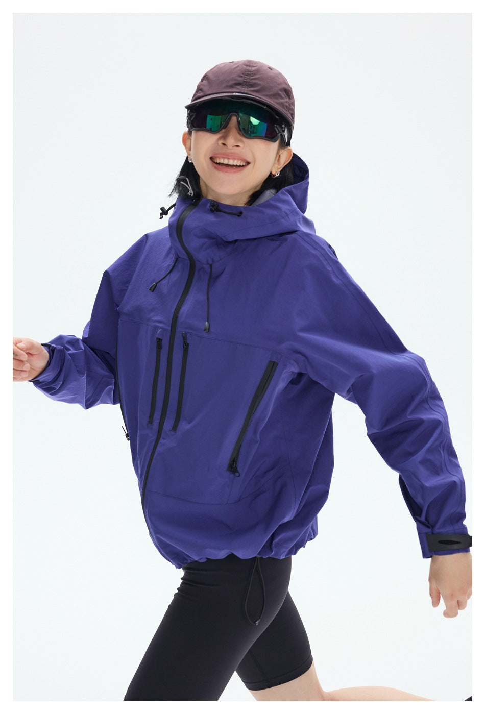 Close view of a model wearing a purple hooded jacket with black front and side zippers.