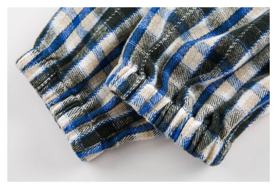 Close-up of gathered plaid fabric and stitched seam in blue, black, and cream.