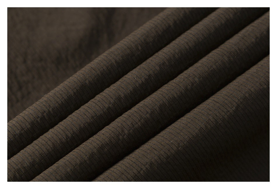 Close-up of dark brown garment fabric arranged in soft folds.