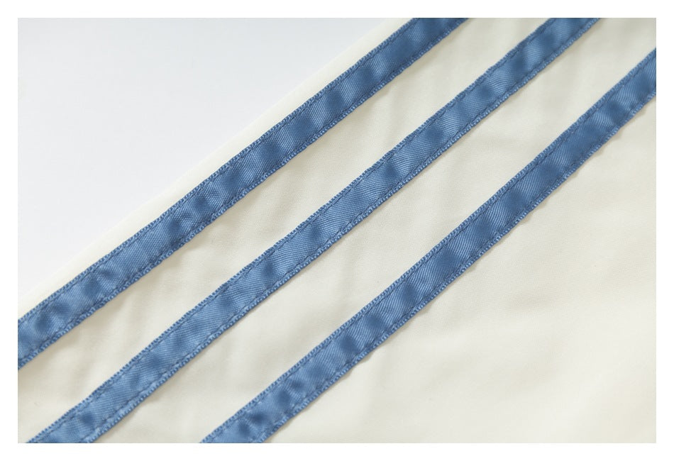 Close-up of three blue stripes running across ivory jacket fabric.