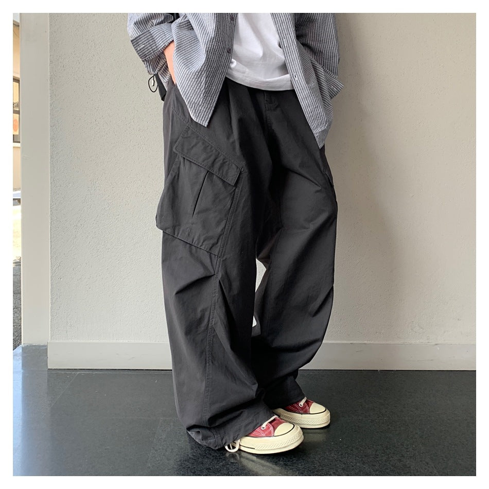 Person wearing dark gray wide-leg cargo pants with a large flap pocket, striped shirt and red sneakers
