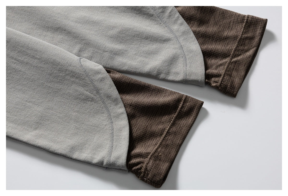 Close-up of two gray sleeves ending in brown ribbed cuffs.